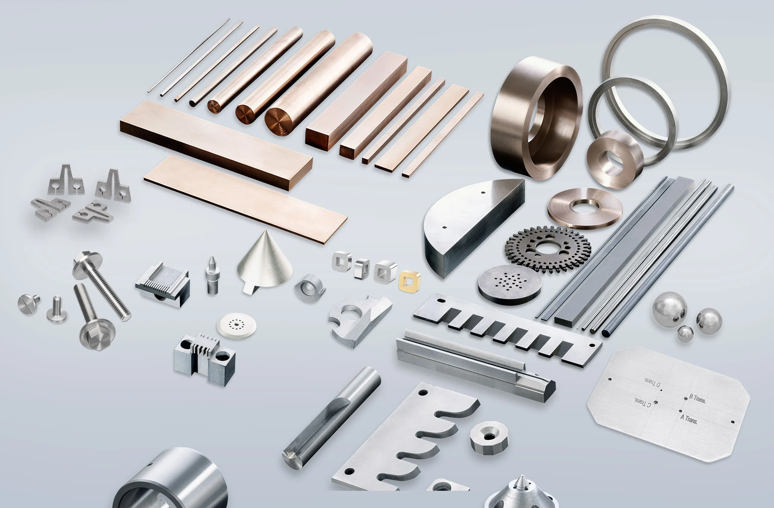 Assorted machined metal parts, rods, plates, rings, and components of various shapes, sizes, and finishes are arranged neatly on a light gray background.