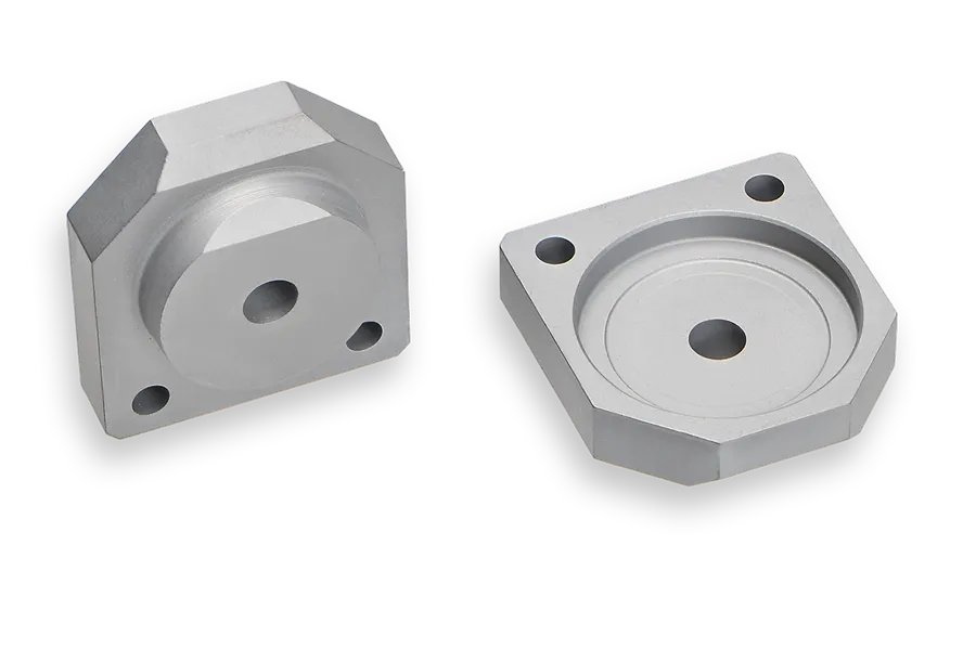 Two silver, hexagonal metal parts with circular depressions and central holes, each featuring four smaller holes near the corners, are shown on a white background.