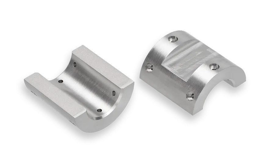 Two curved, silver metal brackets with four screw holes each, displayed side by side on a black background. One bracket shows a smooth concave surface, while the other displays a machined flat area.