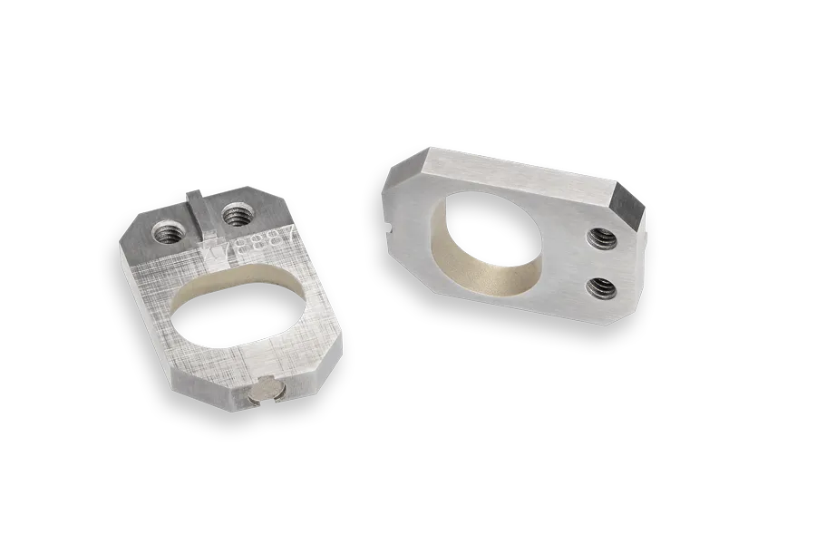 Two rectangular metal brackets with rounded edges and large oval holes in the center, each with two smaller threaded holes on one side, placed on a black background.